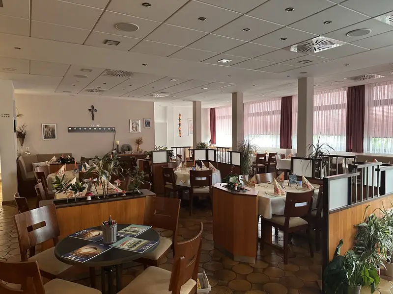 Gastraum des Restaurant Bürgerhaus Zellhausen mit eingedeckten Tischen, Raumteilern aus Holz und Pflanzen